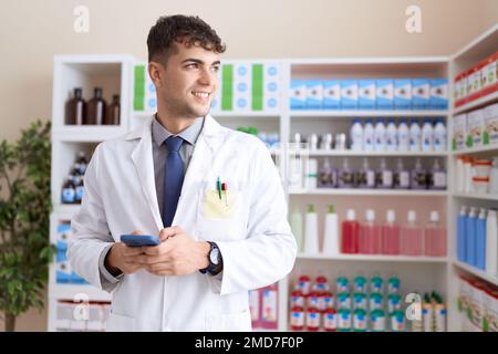 Junger hispanic-Mann Apotheker mit Smartphone in der Apotheke arbeiten Stockfoto