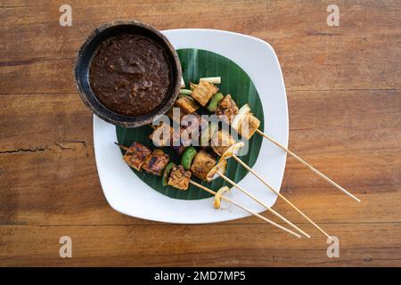 Blick von oben auf veganen Satay-Spieß mit Tofu und Tempeh mit Erdnusssoße, horizontal Stockfoto