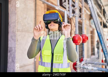 Junge schöne hispanische Architektin mit Virtual-Reality-Brille auf der Straße Stockfoto