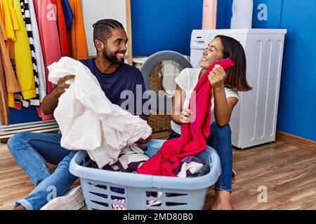 Mann und Frau lächeln selbstbewusst beim Waschen von Kleidung Stockfoto
