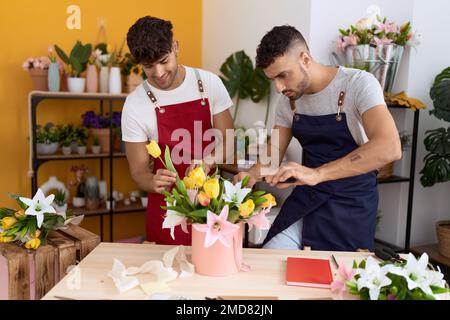 Zwei hispanische Blumenhändler, die selbstbewusst lächeln, machen einen Blumenstrauß im Blumenladen Stockfoto