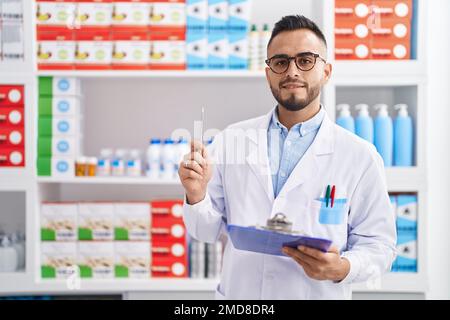 Junger hispanischer Apotheker, der auf einem Dokument in der Apotheke schreibt Stockfoto