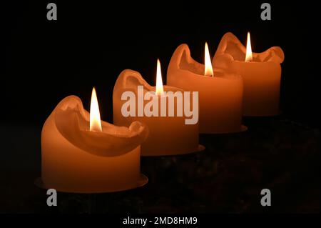 Vier Adventskerzen, alle im Fokus, in der Dunkelheit, schaffen eine warme und friedliche Atmosphäre Stockfoto