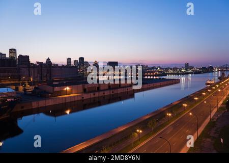 Blick auf die Pierre-Dupuy Avenue und den Hafen von Montreal mit der Skyline der Stadt in der Abenddämmerung, Quebec, Kanada. Stockfoto