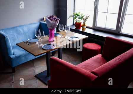 Im Inneren des Cafés stehen leere Sessel in einem Restaurant vor dem Hintergrund einer Backsteinmauer mit Spiegeln. Hochwertiges Foto Stockfoto