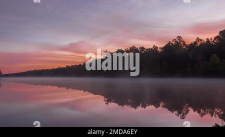 Die Sonne geht über einem wunderschönen, nebeligen See auf. Stockfoto