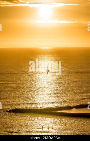 Sonnenuntergang über einem einzelnen Segelboot vor Magic Island auf Oahu, Hawaii Stockfoto