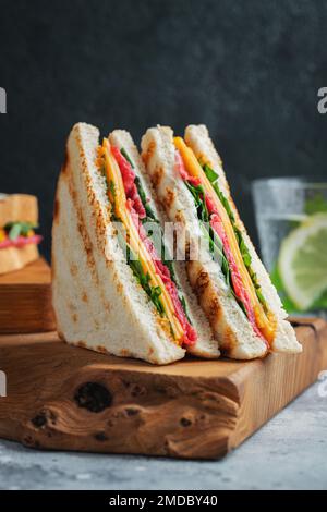 Zwei hausgemachte Sandwiches mit Wurst, Käse und Rucola auf hellem Betonhintergrund Stockfoto