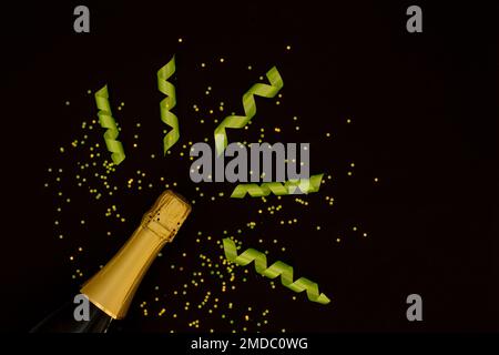 Champagner mit Partykonzept, Champagnerflasche mit Band und Konfetti-Sternen im Hintergrund. Stockfoto