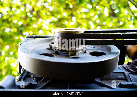 Angetriebene Riemenscheibe eines fahrbaren Traktors mit zwei Riemen Nahaufnahme auf einem unscharfen Hintergrund. Motor für kleine Traktoren für die Gartenbearbeitung Stockfoto