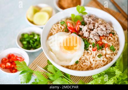 Nudelschüssel mit gekochtem Ei Hackfleisch Schweinefleisch Gemüse Frühlingszwiebeln Zitrone Limette Salat Sellerie und Chili auf dem Tisch Essen, Instantnudeln kochen leckeres Essen Stockfoto