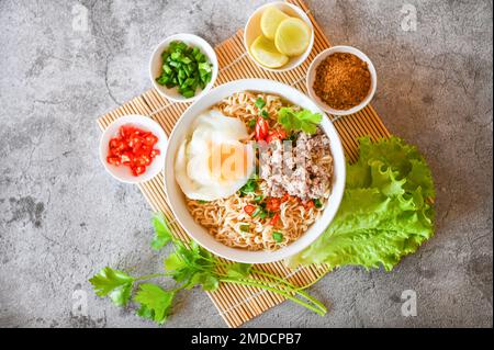 Nudelschüssel mit gekochtem Ei Hackfleisch Schweinefleisch Gemüse Frühlingszwiebeln Zitrone Limette Salat Sellerie und Chili auf dem Tisch Essen, Instantnudeln kochen leckeres Essen Stockfoto