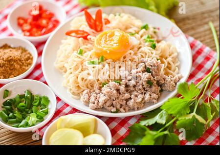 Nudelteller mit Eierhackfleisch, Gemüse, Frühlingszwiebeln, Zitronensalat, Sellerie und Chili auf dem Tisch, Instant-Nudeln, die köstlich kochen Stockfoto