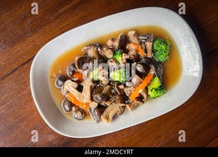 Gebratene Pilze mit Brokkoli-Karotten-Gemüse, Shiitake-Pilze mit Austernsauce kochen Essen auf weißem Teller, Shiitake-Pilze gekocht mit Fryi Stockfoto