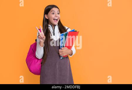 Schockiertes Kind mit Schulrucksack und Arbeitsbuch auf gelbem Hintergrund Stockfoto