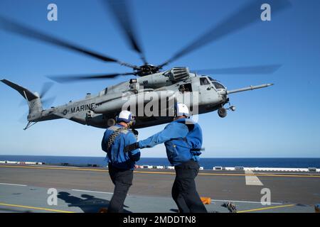 220722-N-XN177-2091 PAZIFIK (22. Juli 2022) – Matrosen wehren sich gegen die Rotorwaschung, während ein dem Marine Medium Tiltrotor Squadron (VMM) 262 (verstärkt) zugeteilter CH-53 Super-Hengst-Helikopter am 22. Juli 2022 auf dem Cockpit an Bord des Amphibien-Angriffsträgers USS Tripoli (LHA 7) landet. Tripolis ist im US-amerikanischen 7.-Flottengebiet tätig, um die Interoperabilität mit Verbündeten und Partnern zu verbessern und als einsatzbereite Eingreiftruppe zur Verteidigung des Friedens und zur Aufrechterhaltung der Stabilität in der Region Indo-Pazifik zu dienen. Stockfoto