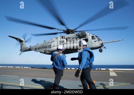 220722-N-XN177-2092 PAZIFIK (22. Juli 2022) – Matrosen wehren sich gegen die Rotorwaschung, während ein dem Marine Medium Tiltrotor Squadron (VMM) 262 (verstärkt) zugeteilter CH-53 Super-Hengst-Helikopter am 22. Juli 2022 auf dem Cockpit an Bord des Amphibien-Angriffsträgers USS Tripoli (LHA 7) landet. Tripolis ist im US-amerikanischen 7.-Flottengebiet tätig, um die Interoperabilität mit Verbündeten und Partnern zu verbessern und als einsatzbereite Eingreiftruppe zur Verteidigung des Friedens und zur Aufrechterhaltung der Stabilität in der Region Indo-Pazifik zu dienen. Stockfoto