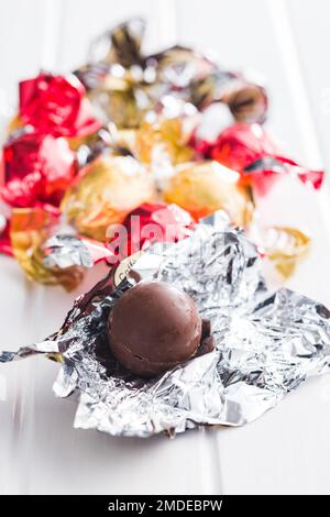 Süße Schokoladenbonbons in Folie auf dem Küchentisch verpackt. Stockfoto