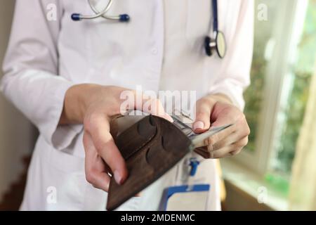 Eine Ärztin steckt Geld in die Tasche. Stockfoto