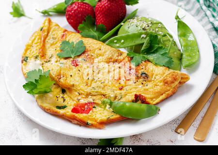 Omelette mit Tomaten, Fetakäse und Avocado auf weißem Teller. Stockfoto