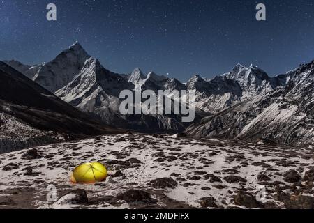 Konzept der Einsamkeit und Freiheit in der Wildnis. Nacht Wintercamping in den Bergen. Einsame Hütte leuchtet von innen in das Tal unter Ama Dablam moun Stockfoto