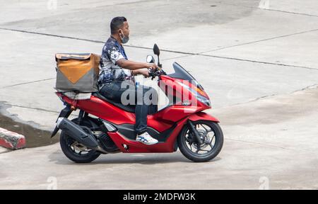 SAMUT PRAKAN, THAILAND, Okt 10 2022, Ein Mann fährt ein Motorrad mit einem Aufbewahrungsfach die Straße runter Stockfoto