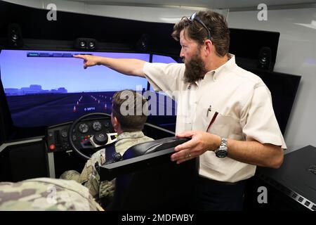 Dozent Patrick Etheradge von der Mississippi Construction Education Foundation trainiert Sergeant Devon Holcomb, ein Motortransportunternehmen der 1687. Transportation Company, Mississippi Army National Guard, in einem Lkw-Fahrsimulator in Camp McCain, Mississippi, 23. Juli 2022. Diese Ausbildung ist Teil eines Programms „Work for Warriors“, das Soldaten, die für den Betrieb schwerer Militärfahrzeuge qualifiziert sind, dabei hilft, einen zivilen gewerblichen Führerschein zu erhalten. Stockfoto