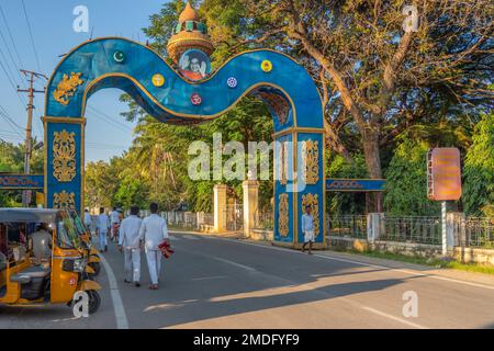 Puttaparthi, Andra Pradesh, Indien - 18,2023. Januar: Der junge Indianer in Weiß schließt den Spaziergang entlang der Straße zum Sai Baba Ashram Stockfoto