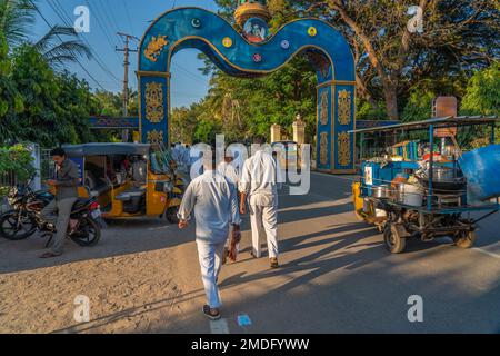 Puttaparthi, Andra Pradesh, Indien - 18,2023. Januar: Der junge Indianer in Weiß schließt den Spaziergang entlang der Straße zum Sai Baba Ashram Stockfoto
