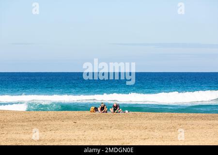 Ein Paar meditiert am Cofete Beach mit dem Rücken zum Meer. Fuerteventura, Kanarische Inseln Stockfoto