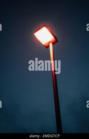 Ein Leuchtpfosten unter einem dunklen Nachthimmel, vertikaler Schuss Stockfoto