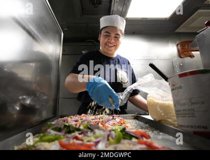 220723-N-DE439-1023 OSTSEE (23. Juli 2022) Spezialistin Selena Palato der 2. Klasse aus San Diego, Kalifornien, bereitet Pizza für das Abendessen an Bord der Arleigh Burke-Klasse-Guided-Missile Destroyer USS Arleigh Burke (DDG 51), 23. Juli 2022, zu. Arleigh Burke ist auf einem geplanten Einsatz in den USA Marinestreitkräfte Europa Einsatzgebiet, angestellt von den USA Sechste Flotte, die die Interessen der USA, Verbündeten und Partner verteidigt. Stockfoto