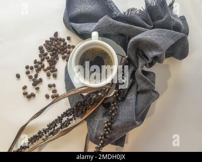 Kaffeeliebhaber, Blick auf Espresso-Tassen dekoriert mit gerösteten Kaffeebohnen und trockenen Blättern, dekorative Elemente, Kaffeeschaum mit Herz... Stockfoto