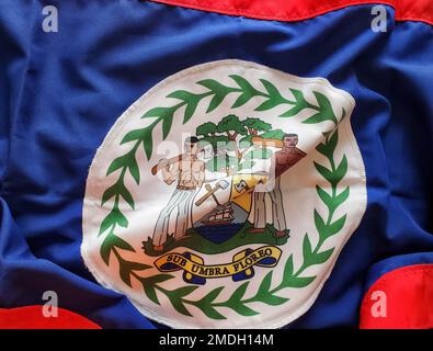Eine Nahaufnahme des weißen runden Wappen auf der winkenden Flagge von Belize Stockfoto