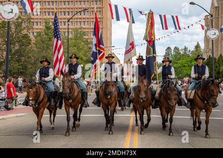 USA Armee-Soldaten, die der berittenen Farbigen Garde des kommandierenden Generals, 1. Infanteriedivision, zugeteilt sind, tragen das National, Wyoming State, USA Army und 1. Inf. Div Farben in einer großen Parade während des 126. Jährlichen Cheyenne Frontier Days Rodeo Kickoff, 23. Juli 2022, in Downtown Cheyenne, Wyoming. Während des 10-tägigen weltweit größten Rodeo-Events unter freiem Himmel, bekannt als „Daddy of „EM All“, das 1. Inf. Div Die CGMCG führte die Eröffnungszeremonie mit den Farben durch, nahm an großen Paraden Teil und führte ihre Taktik-Demonstration der montierten Kavallerie durch. Stockfoto