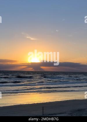 Eine malerische Aufnahme des goldenen Sonnenuntergangs am Ozeanhorizont, der sich von den Wellen reflektiert Stockfoto