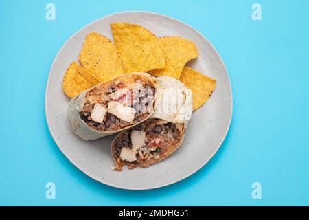 Mexikanischer Rindfleischburrito auf einem kleinen Teller mit Chips Nachos auf dem Teller Stockfoto