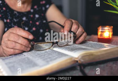 Eine alte Frau liest die Bibel, die Hände sind dicht. Stockfoto