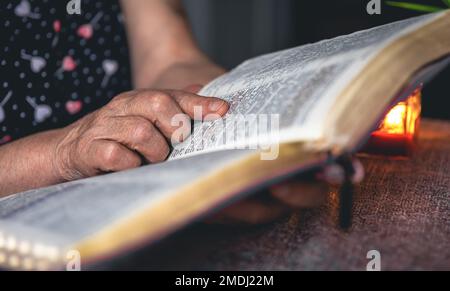Eine alte Frau liest die Bibel, die Hände sind dicht. Stockfoto
