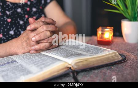 Eine alte Frau liest die Bibel, die Hände sind dicht. Stockfoto