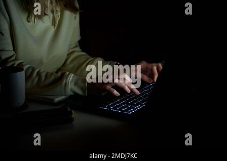 Nahaufnahme einer anonymen Frau, die nachts auf der Laptop-Tastatur tippt. Konzept der Online-Kommunikation und Arbeit außerhalb der Geschäftszeiten Stockfoto