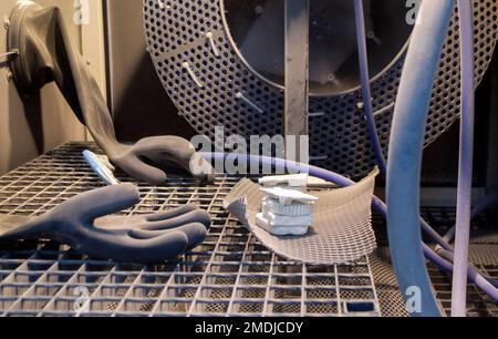 Auf einem 3D-Drucker gedruckte Modelle aus weißem Polyamidpulver in einer Strahlmaschine zur Reinigung. Innenschuss-Sprengmaschine. Öffnen Sie die Maschine, um Objekte zu schießen. Industriemaschinen Stockfoto
