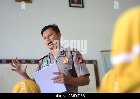 Ein Polizist unterrichtet einen schüler der Grundschule. Er erklärt seine Arbeit als Polizist, um den Schüler zu inspirieren. Stockfoto