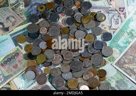 Alte Münzen auf verschiedenen alten Bargeld-Banknoten aus verschiedenen Ländern der Welt, ein Haufen verschiedener Währungen, ein Haufen alter Retro-Scheine Stockfoto