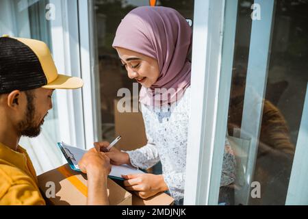 Weibliche Kundin im Schleier beim Empfang von Liefermännern Stockfoto
