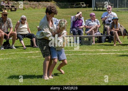 Zwei junge Jungs, die im malerischen Grün von St. Mawgan in Pydar in Cornwall in England am Grand Cornish Wrestling Tournament teilnehmen Stockfoto