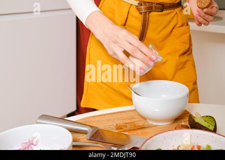 Nahaufnahme von weiblichen Händen, die Salat mit Salz streuen Stockfoto