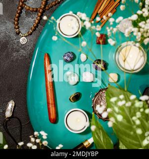 Pflegeleichte, heilende Komposition mit Rosenkranz, Duftstäbchen, Chakra-Steinen, Sandelholz-Stäbchen und Kerze auf einem grünen Marmorpodium. Konzept der Entspannung Stockfoto