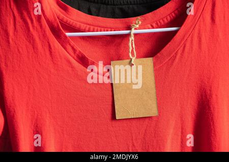 Karton, Verpackung, lässig, Kleidung, Branding, Shopping, braunes Papier Preisschild wiegt auf Kleidung auf einem Rack auf einem Kleiderbügel im Verkaufsbereich, blank pri Stockfoto