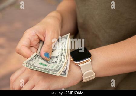 Smart Watch auf der Hand des Mädchens nahm Dollarscheine auf der Straße, Geld und Smart Watch Stockfoto